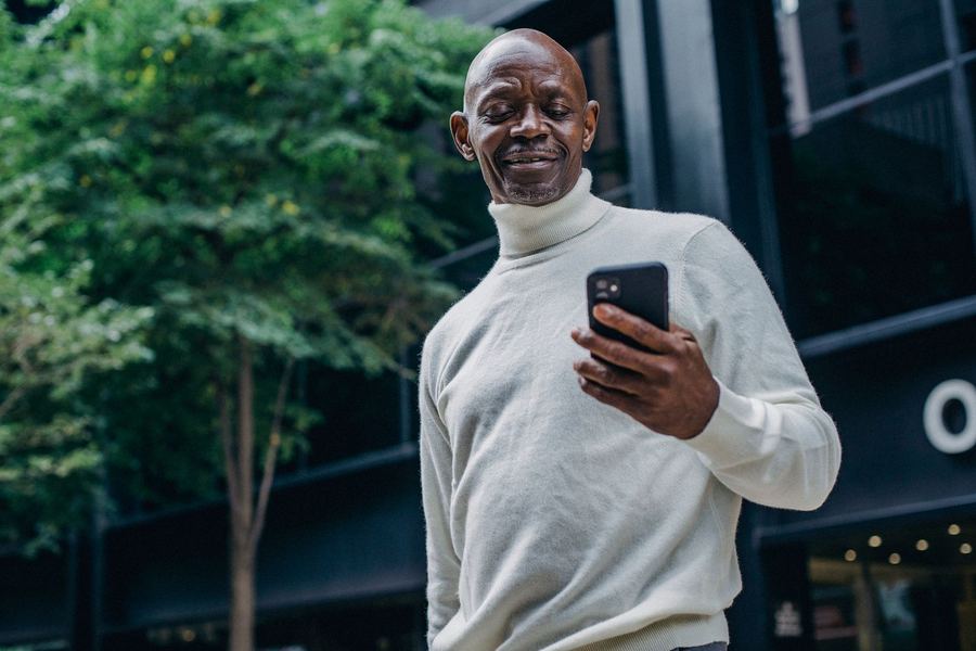 Un homme souriant devant son téléphone en ville